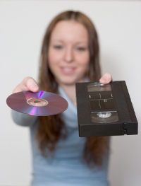 Woman holding DVD and VHS tape.